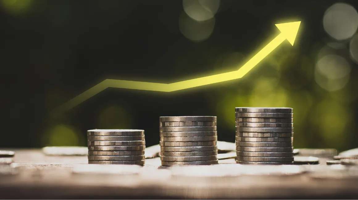 Stosy monet z rosnącą żółtą strzałką symbolizującą wzrost finansowy